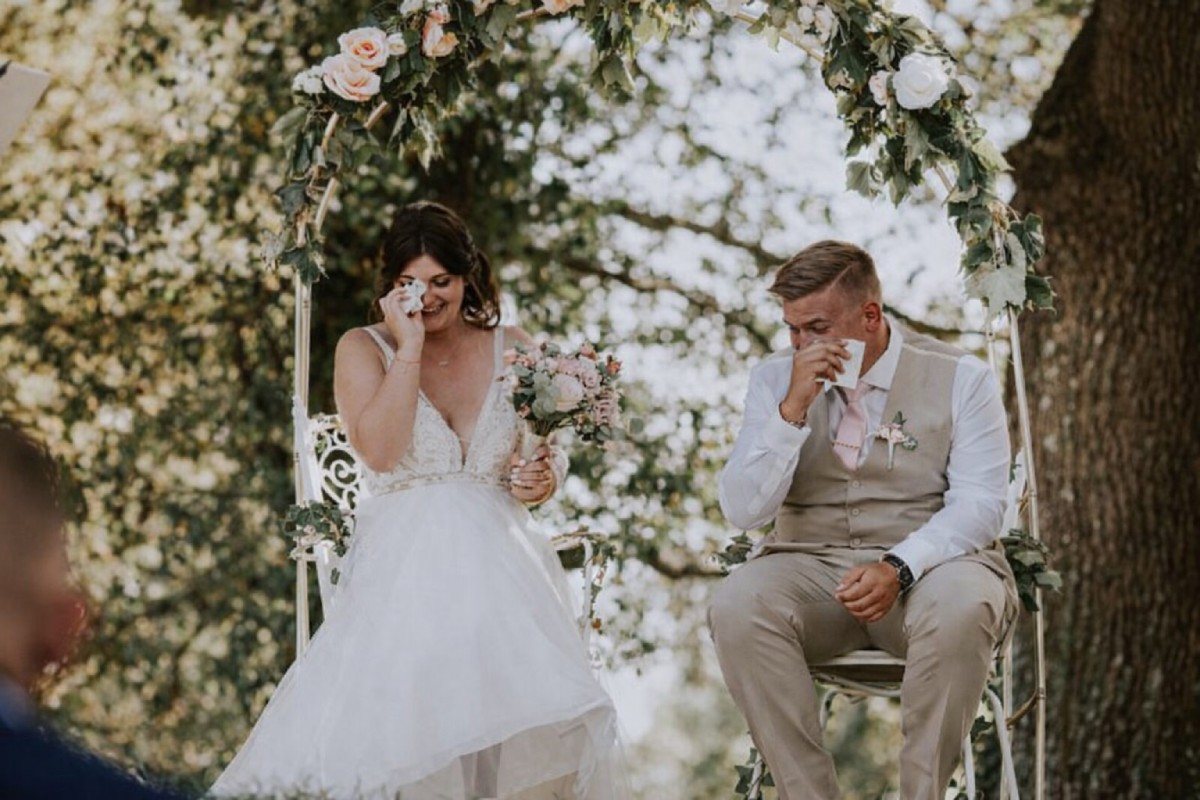Mariés émus lors de leurs vœux de mariage sous une arche fleurie en extérieur, moment intime d’une cérémonie romantique - Laveran Paris